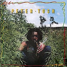 In a forest, Peter Tosh is seen smoking from a pipe.