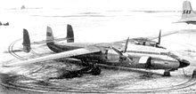 Photograph of two-engine turboprop aircraft with three vertical stabilisers parked on snow-covered ramp