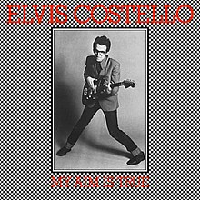A man with glasses in a pigeon-toed stance holding a guitar surrounded by a checkerboard pattern. The words "Elvis Costello" are at the top while "My Aim Is True" is at the bottom.