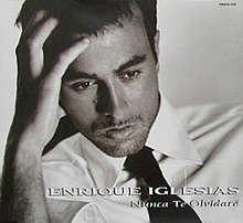 Black-and-white photo of Enrique Iglesias wearing a white buttoned shirt and a black tie.